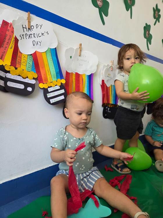 Bebês da Creche Escola Santa Beatriz brincando diante dos cartazes em inglês feitos pela turma no Projeto Bilíngue