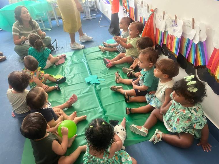 Turma do Berçário da Creche Escola Santa Beatriz sentada em roda com a professora numa atividade do Projeto Bilíngue