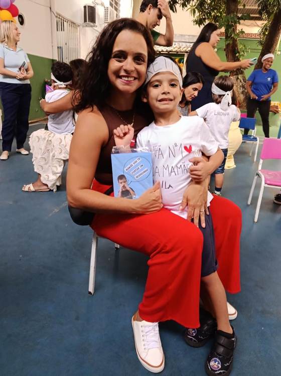 Mãe com o filho no colo na comemoração do Dia das Mães da Creche Escola Santa Beatriz