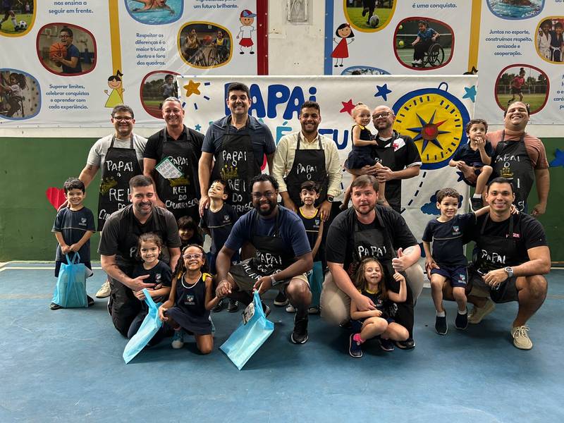 Pais e filhos reunidos na quadra da Creche Escola Santa Beatriz na comemoração do Dia dos Pais, com aventais personalizados