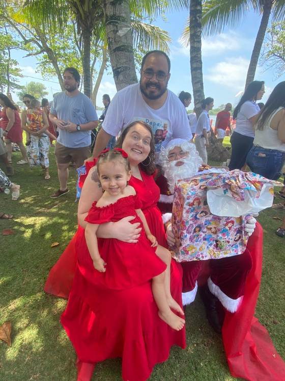 Família de aluna da Creche Escola Santa Beatriz com o Papai Noel durante a Festa da Família, ao ar livre