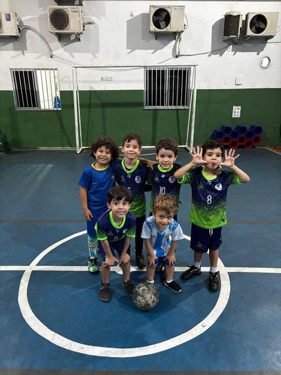 Time de futsal da Creche Escola Santa Beatriz posando com a bola no centro da quadra