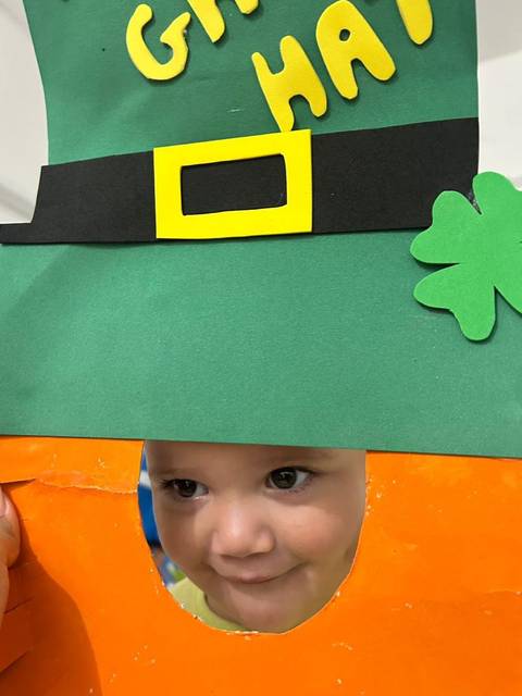 Aluno da Creche Escola Santa Beatriz espiando pelo painel de chapéu de trevo no Saint Patrick's Day